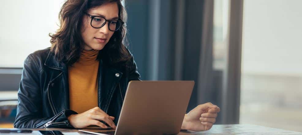 Frau mit Brille sitzt vor Laptop