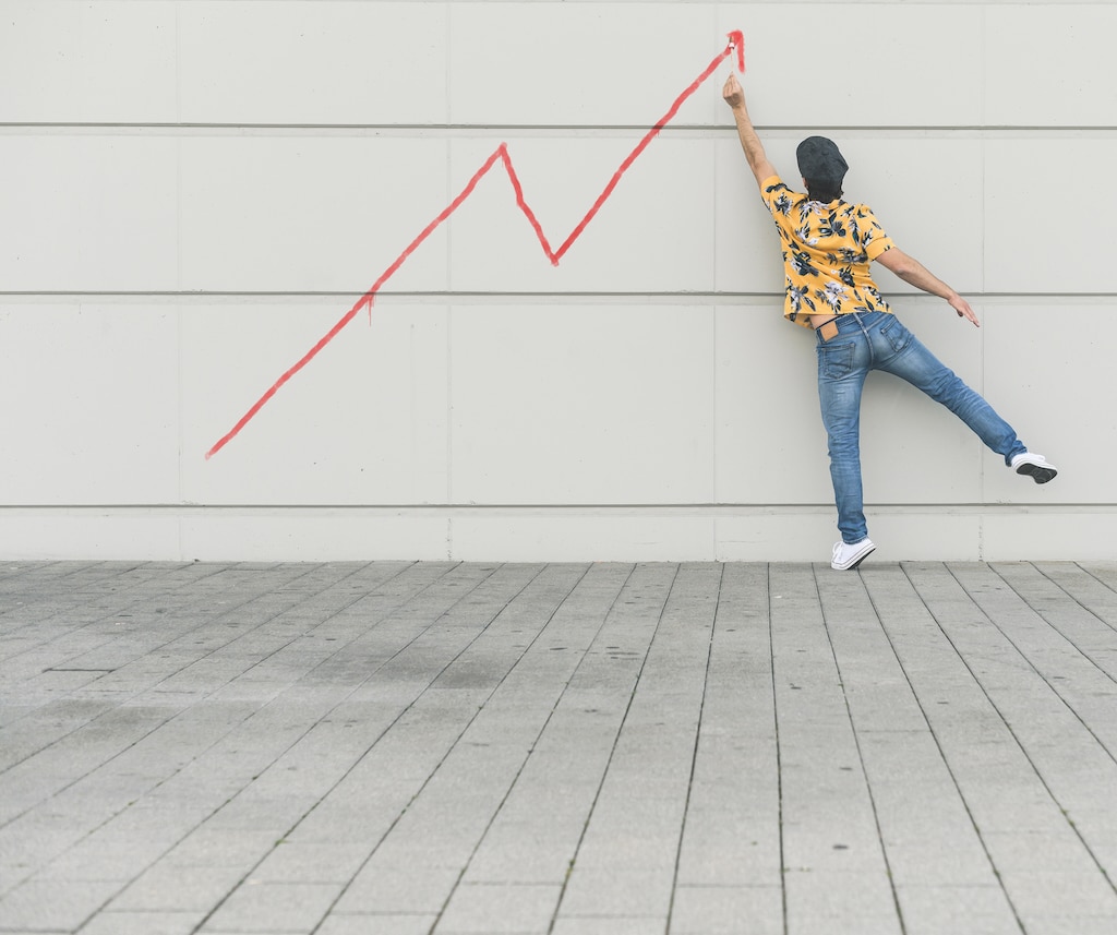 Digital composite of young man drawing a line graph at a wall