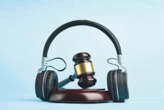 Music copyright law concept. Headphones and judge gavel background with copy-space. Music piracy and owners rights