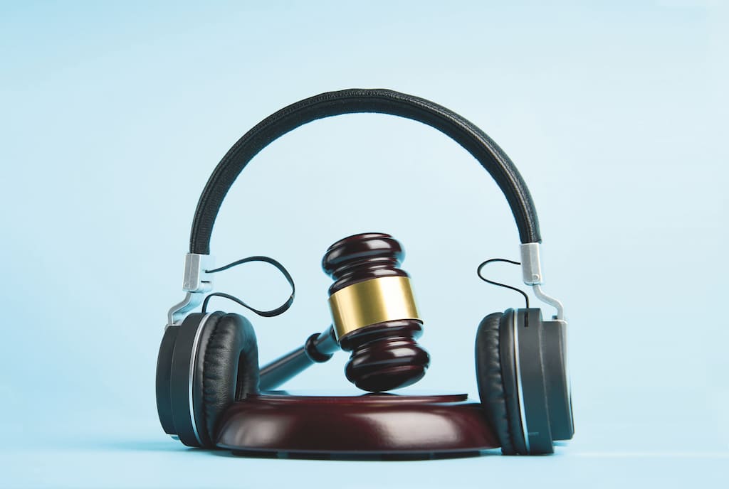 Music copyright law concept. Headphones and judge gavel background with copy-space. Music piracy and owners rights